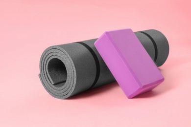Photo of Grey exercise mat and yoga block on pink background