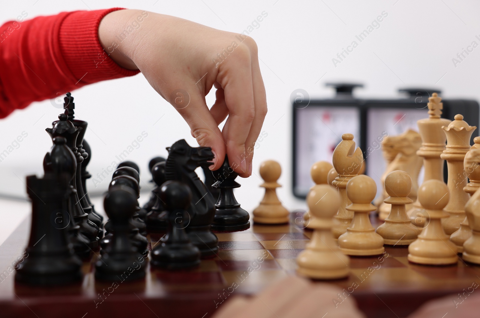 Photo of Little child playing chess at table indoors, closeup