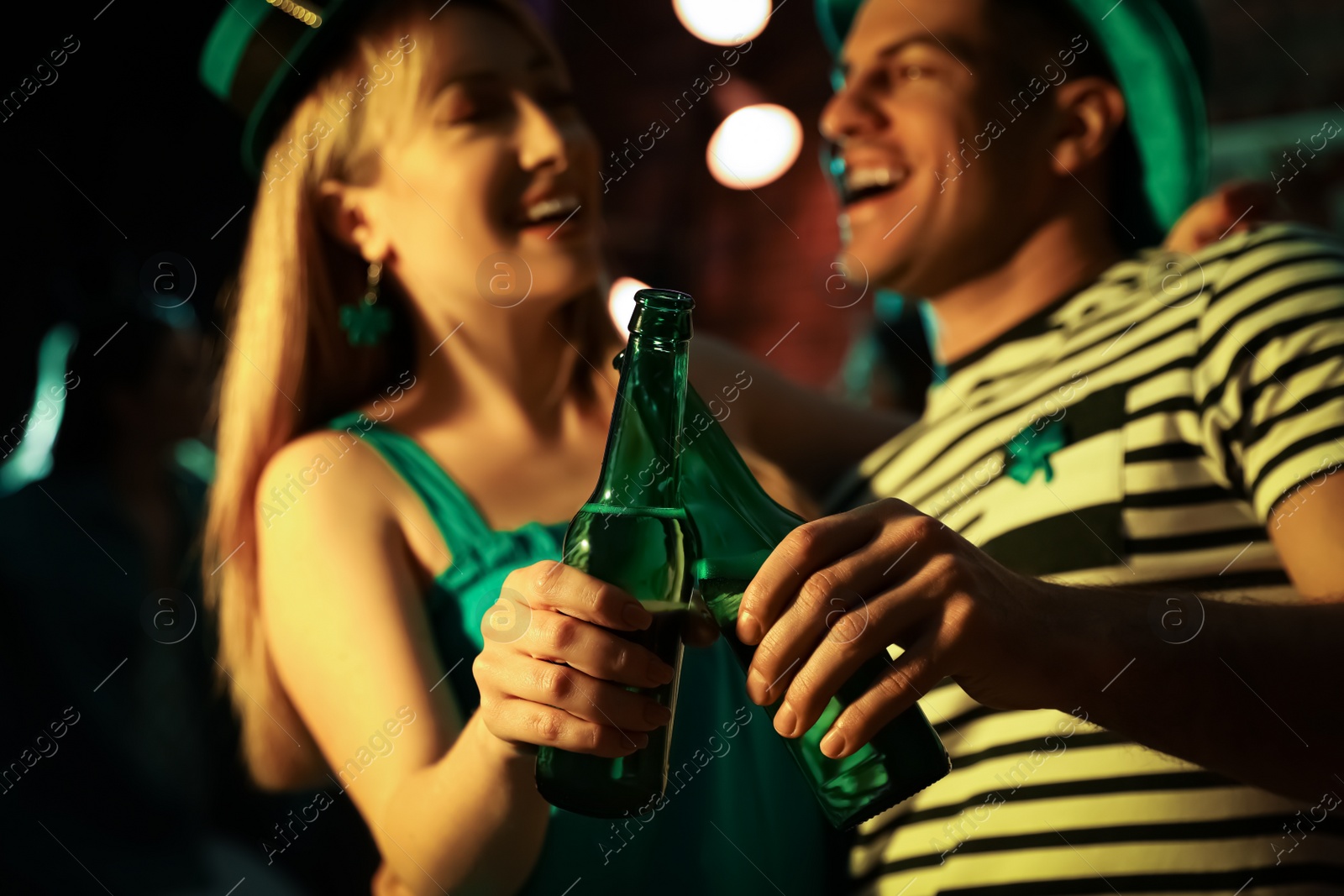 Photo of Couple with beer celebrating St Patrick's day in pub, focus on hands