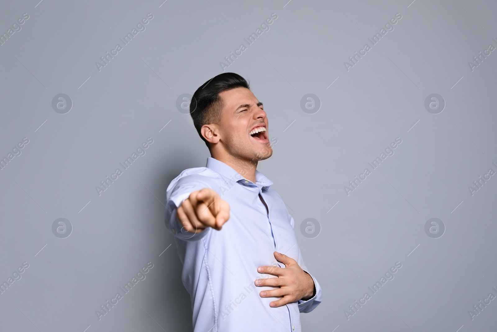 Photo of Handsome man laughing on grey background. Funny joke