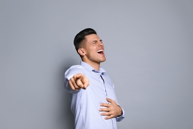 Handsome man laughing on grey background. Funny joke