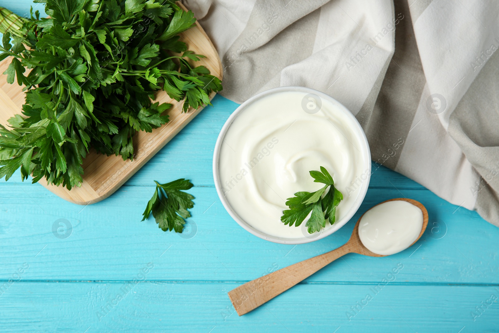 Photo of Flat lay composition with sour cream and parsley on light blue wooden table