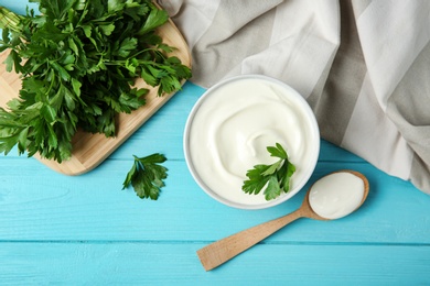 Photo of Flat lay composition with sour cream and parsley on light blue wooden table