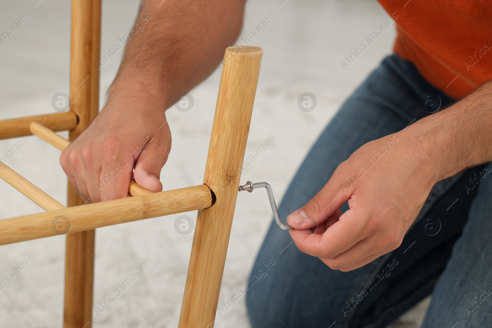 Photo of Man with hex key assembling furniture indoors, closeup