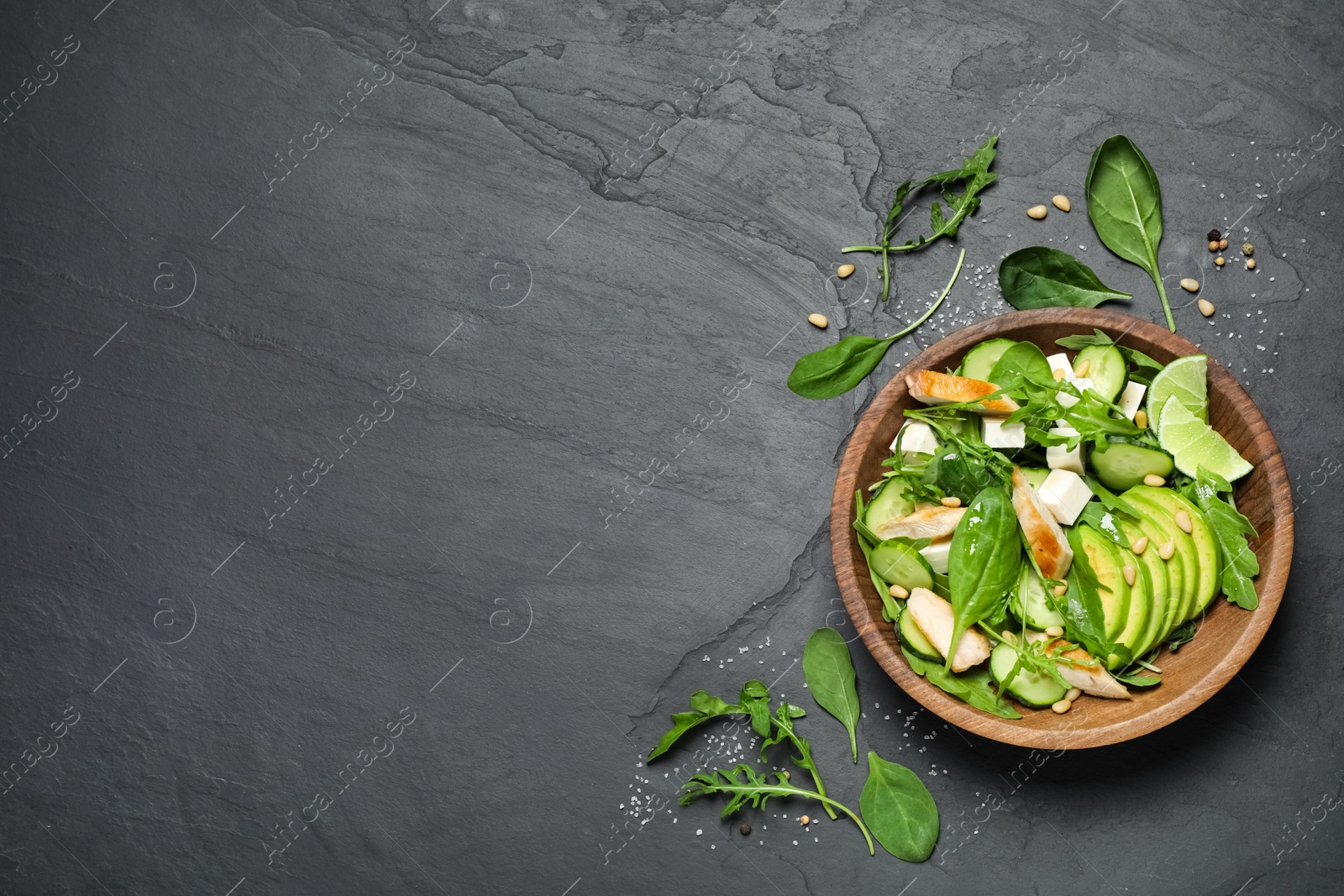 Photo of Delicious salad with chicken, arugula and avocado on black table, flat lay. Space for text