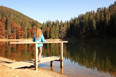 Woman enjoying view of autumn forest near lake