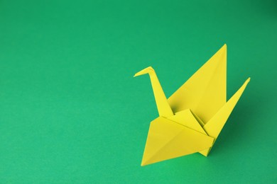 Photo of Paper origami crane on green background, space for text
