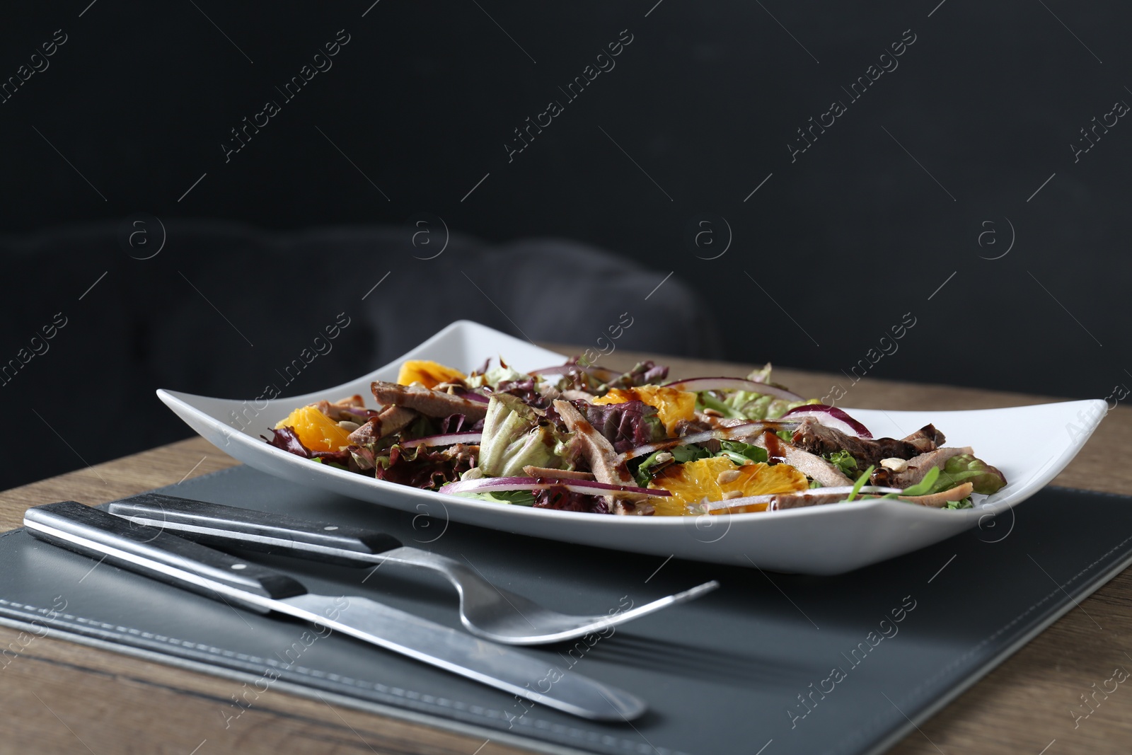 Photo of Delicious salad with beef tongue, orange and onion served on wooden table