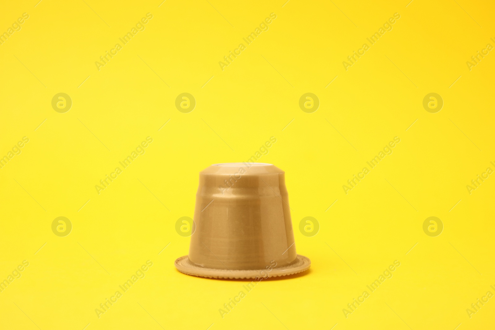 Photo of One plastic coffee capsule on yellow background