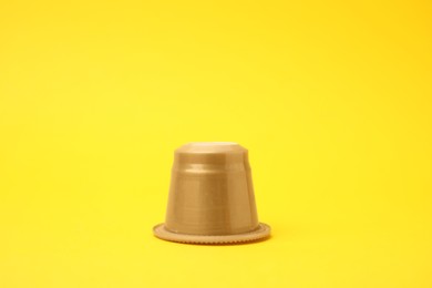 Photo of One plastic coffee capsule on yellow background