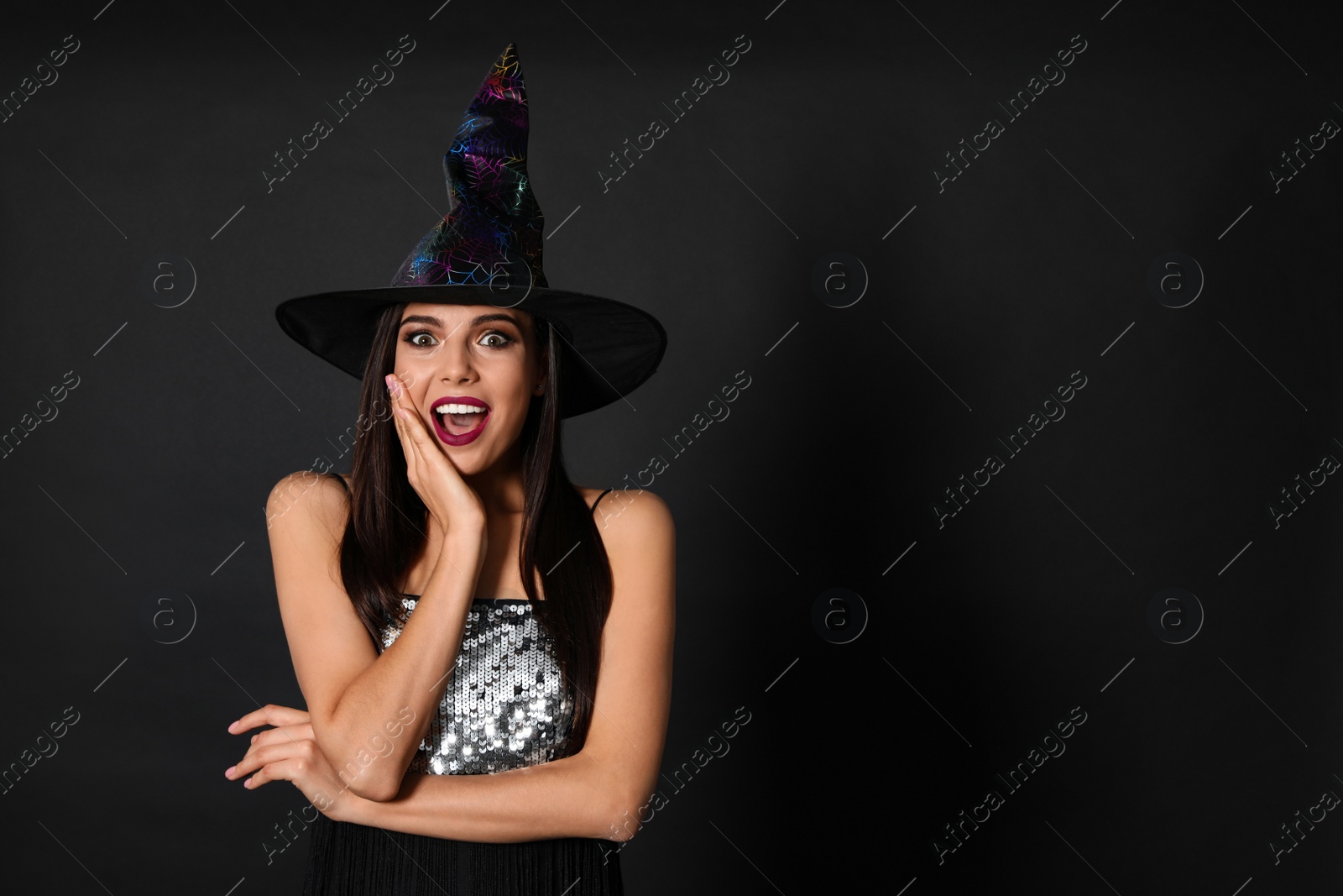 Photo of Excited woman wearing witch costume for Halloween party on black background, space for text