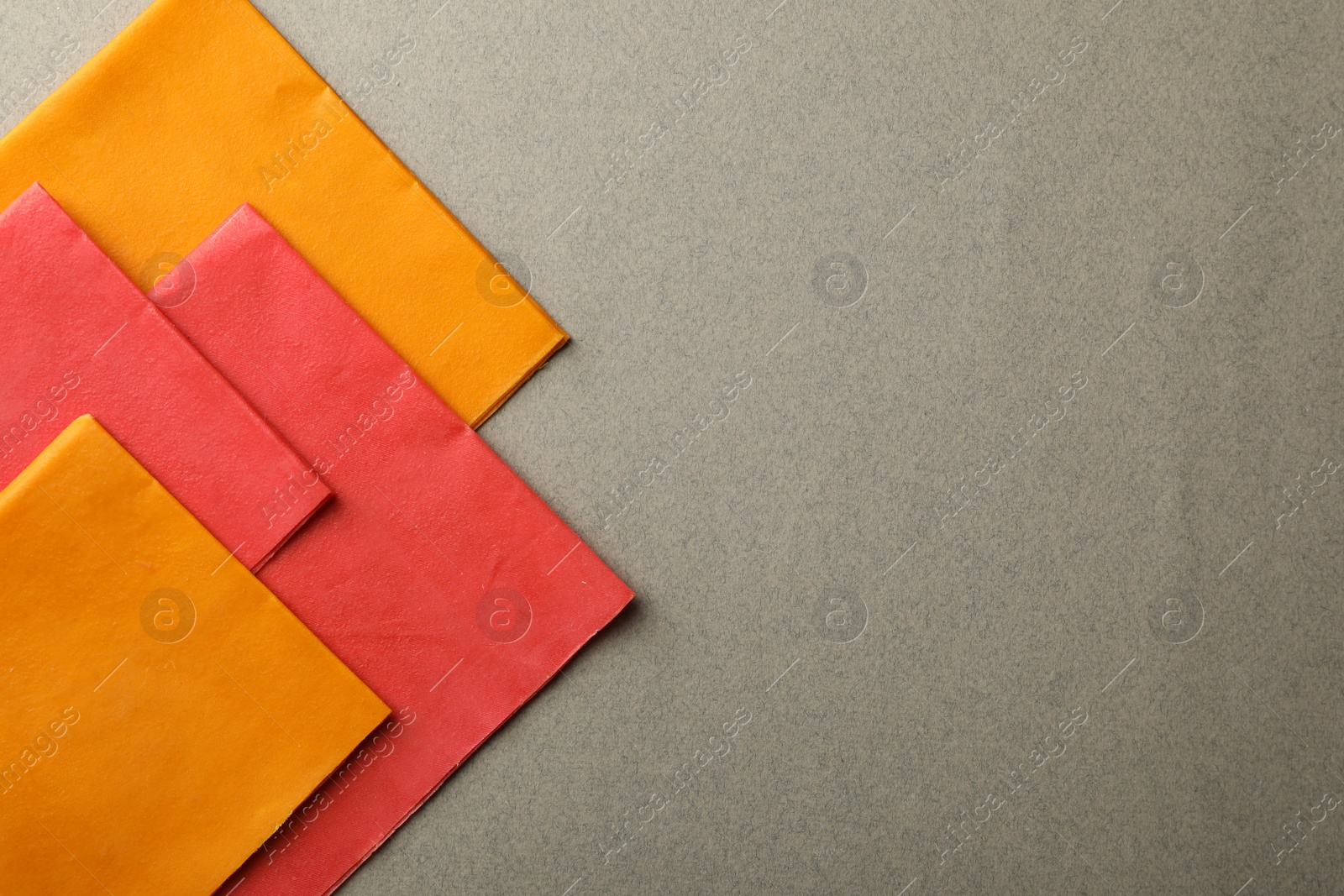 Photo of Colorful reusable beeswax food wraps on grey background, top view. Space for text