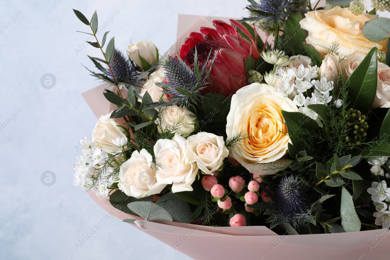 Photo of Beautiful bouquet with roses on light blue background, closeup