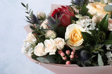 Photo of Beautiful bouquet with roses on light blue background, closeup