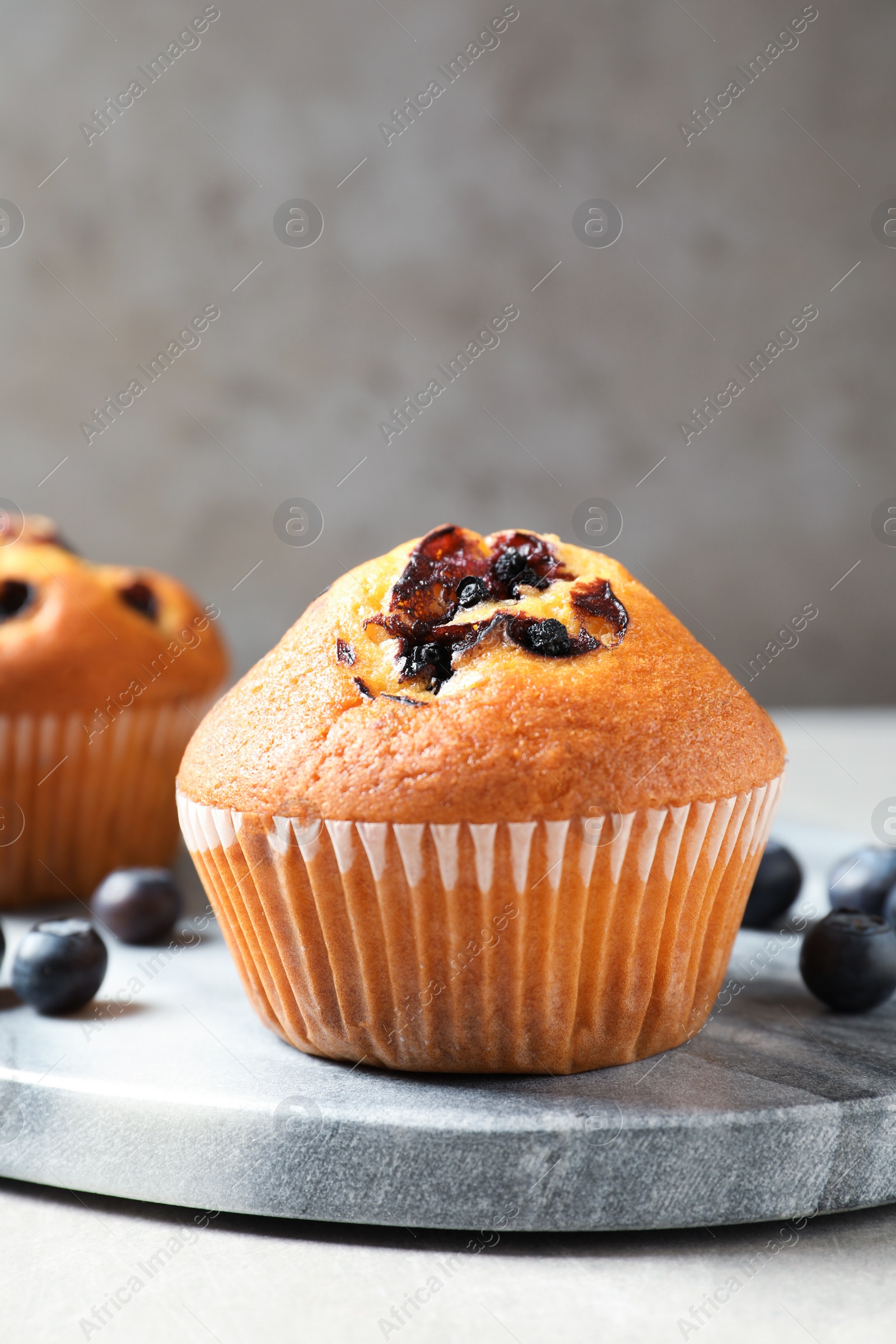 Photo of Stone board with blueberry muffins on light table, closeup view. Space for text