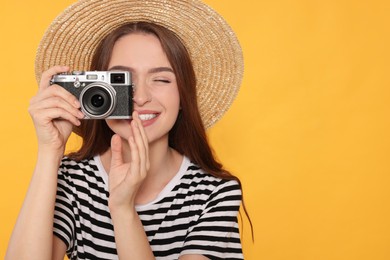 Photo of Young woman with camera taking photo on yellow background, space for text. Interesting hobby