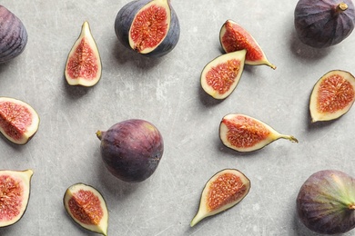 Flat lay composition with whole and cut purple figs on gray background