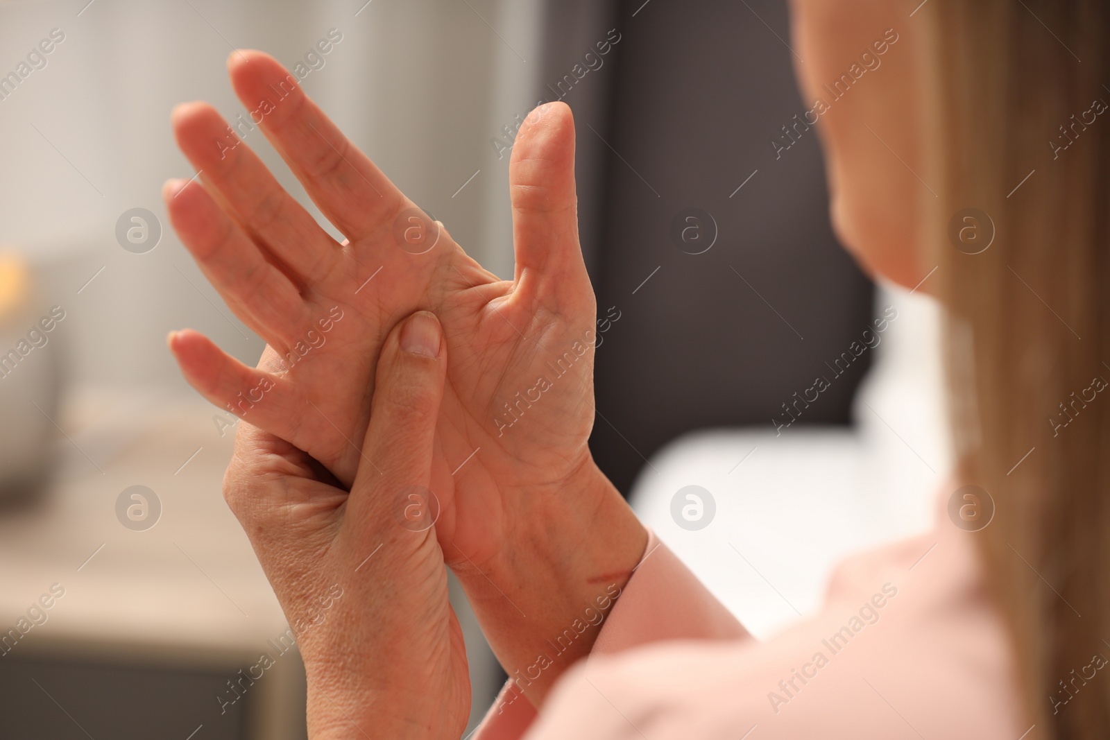 Photo of Mature woman suffering from pain in hand indoors, closeup. Rheumatism symptom