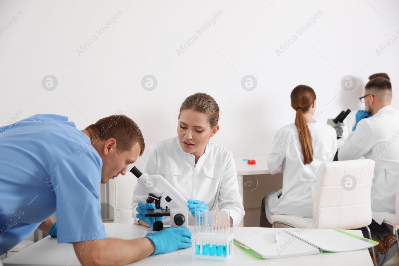 Photo of Medical students working with microscope in modern laboratory