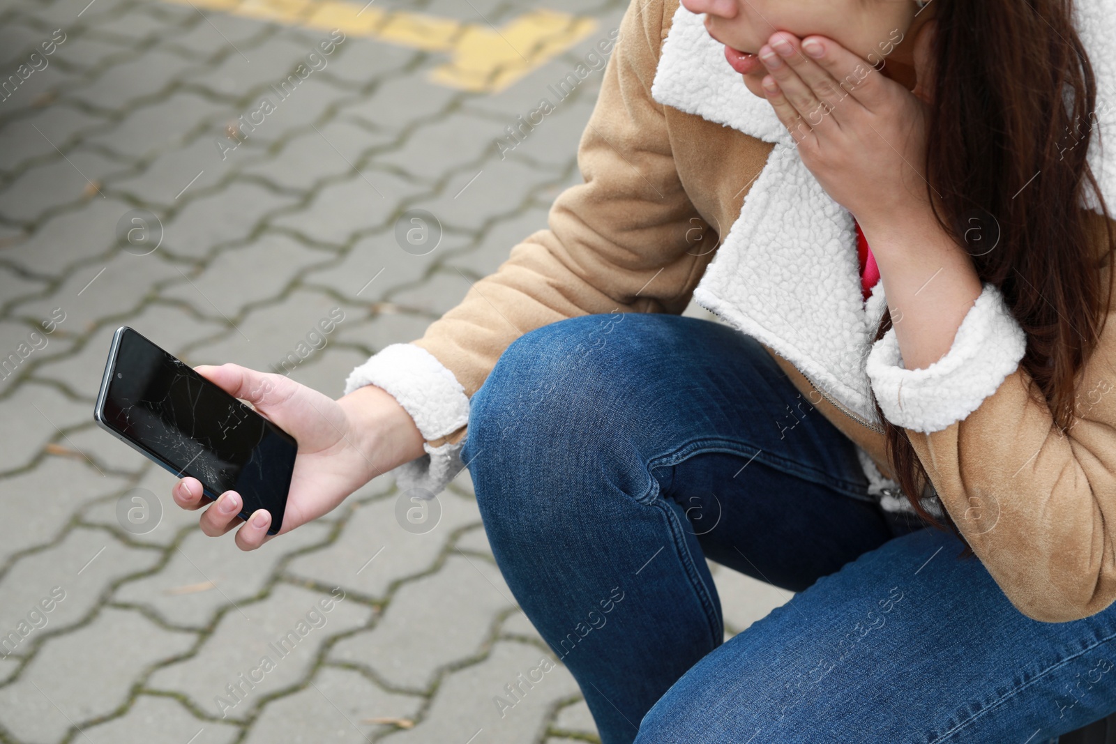 Photo of Woman holding damaged smartphone outdoors, closeup. Device repairing