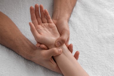 Woman receiving hand massage on soft towel, above view