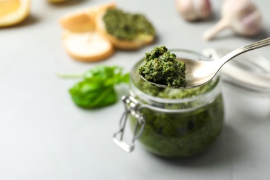 Photo of Spoon with basil pesto sauce and space for text on blurred background