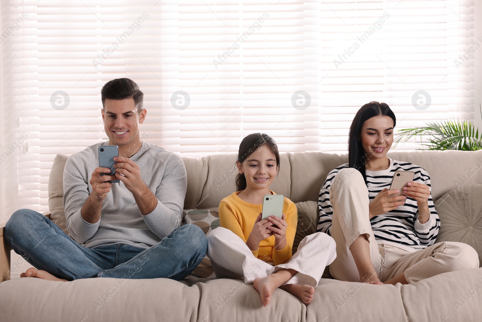 Photo of Internet addiction. Family with gadgets on sofa in living room