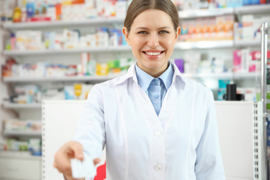 Image of Professional pharmacist with pills in modern drugstore
