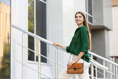 Photo of Beautiful young woman with stylish leather bag outdoors on summer day