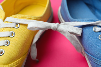 Photo of Shoes tied together on pink background, closeup. April Fool's Day