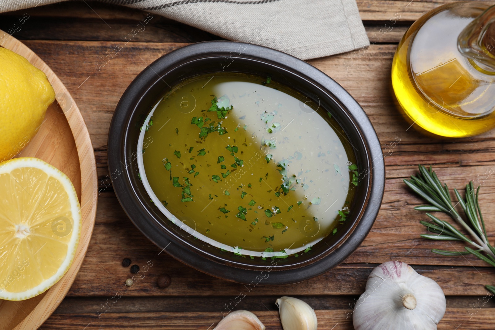 Photo of Bowl with lemon sauce and ingredients on wooden table, flat lay. Delicious salad dressing