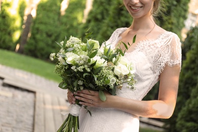 Photo of Bride in beautiful wedding dress with bouquet outdoors, closeup