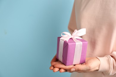 Photo of Woman holding gift box on light blue background,  space for text. Valentine's Day celebration