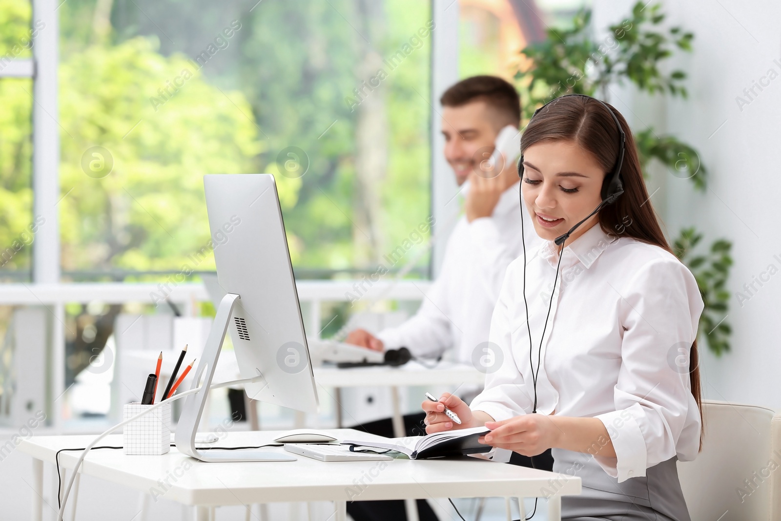 Photo of Female receptionist with headset at desk in office