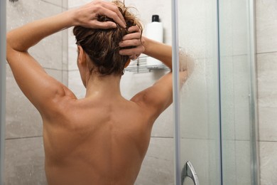 Photo of Woman washing hair in shower stall, back view