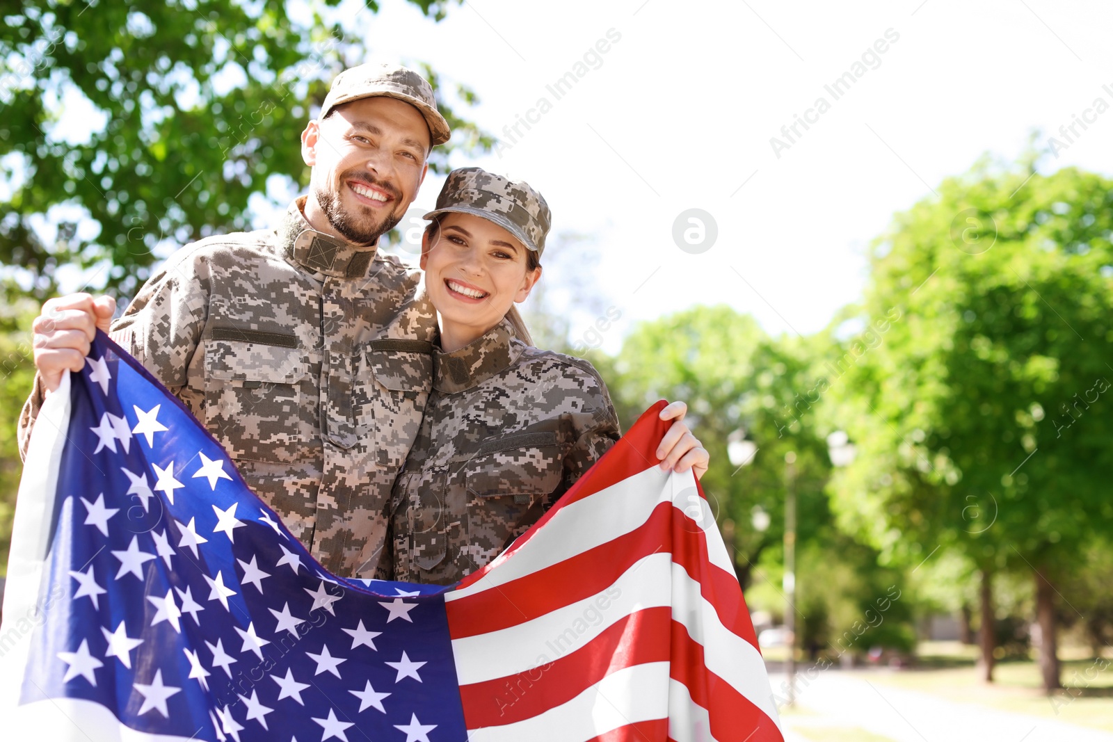 Photo of Military couple with American flag in park