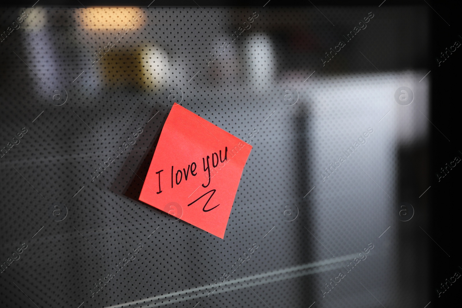 Photo of Sticky note with handwritten text I Love You attached to oven door in kitchen. Romantic message