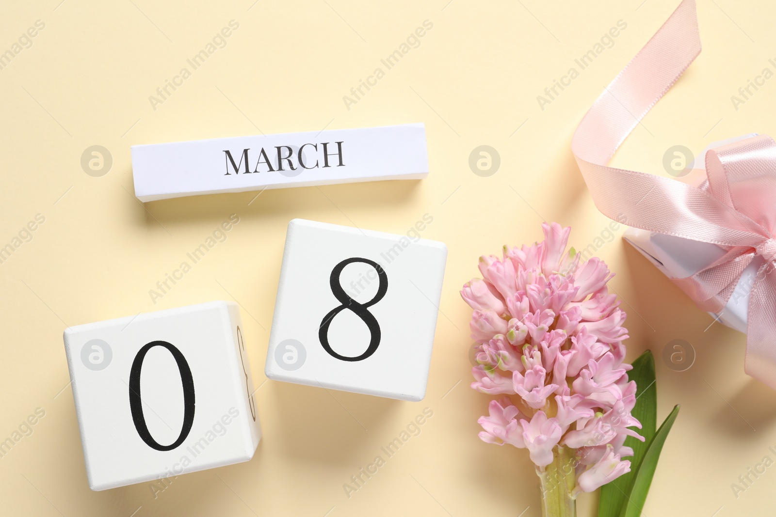 Photo of International Women's day - 8th of March. Gift box, wooden block calendar and beautiful flowers on beige background, flat lay