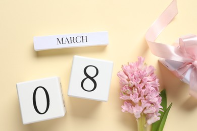 International Women's day - 8th of March. Gift box, wooden block calendar and beautiful flowers on beige background, flat lay