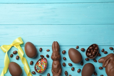 Flat lay composition with chocolate Easter eggs on color wooden background, space for text