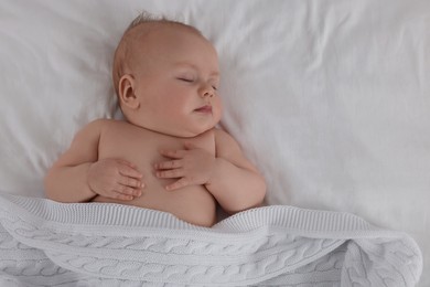 Cute newborn baby sleeping under plaid on bed, top view