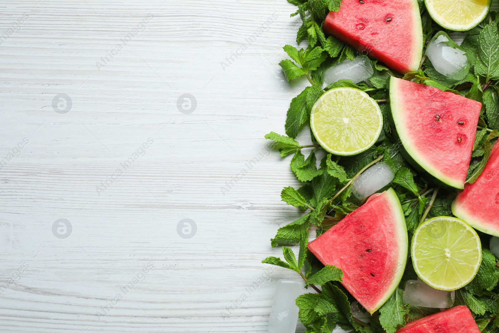 Photo of Tasty sliced watermelon, limes, mint and ice on white wooden table, flat lay. Space for text