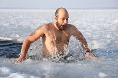 Photo of MYKOLAIV, UKRAINE - JANUARY 06, 2021: Man immersing in icy water on winter day