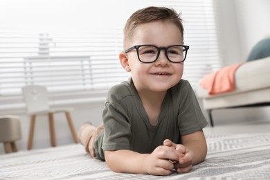 Cute little boy in glasses on floor at home. Space for text