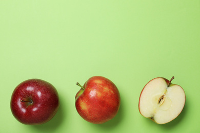 Tasty red apples on green background, flat lay. Space for text