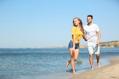 Photo of Happy young couple walking at beach on sunny day