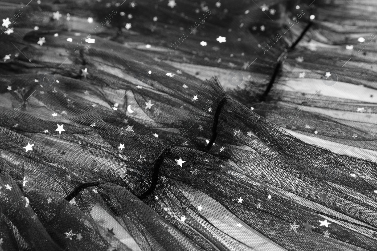 Photo of Beautiful black tulle fabric with shiny stars as background, closeup