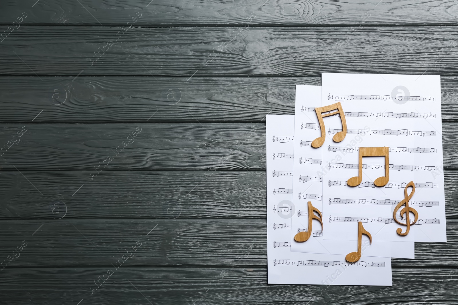 Photo of Sheets and music notes on wooden background, top view. Space for text