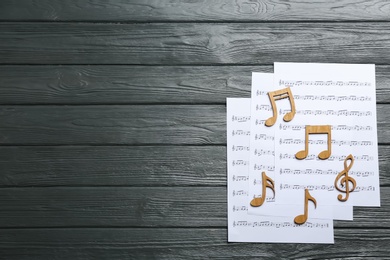 Photo of Sheets and music notes on wooden background, top view. Space for text