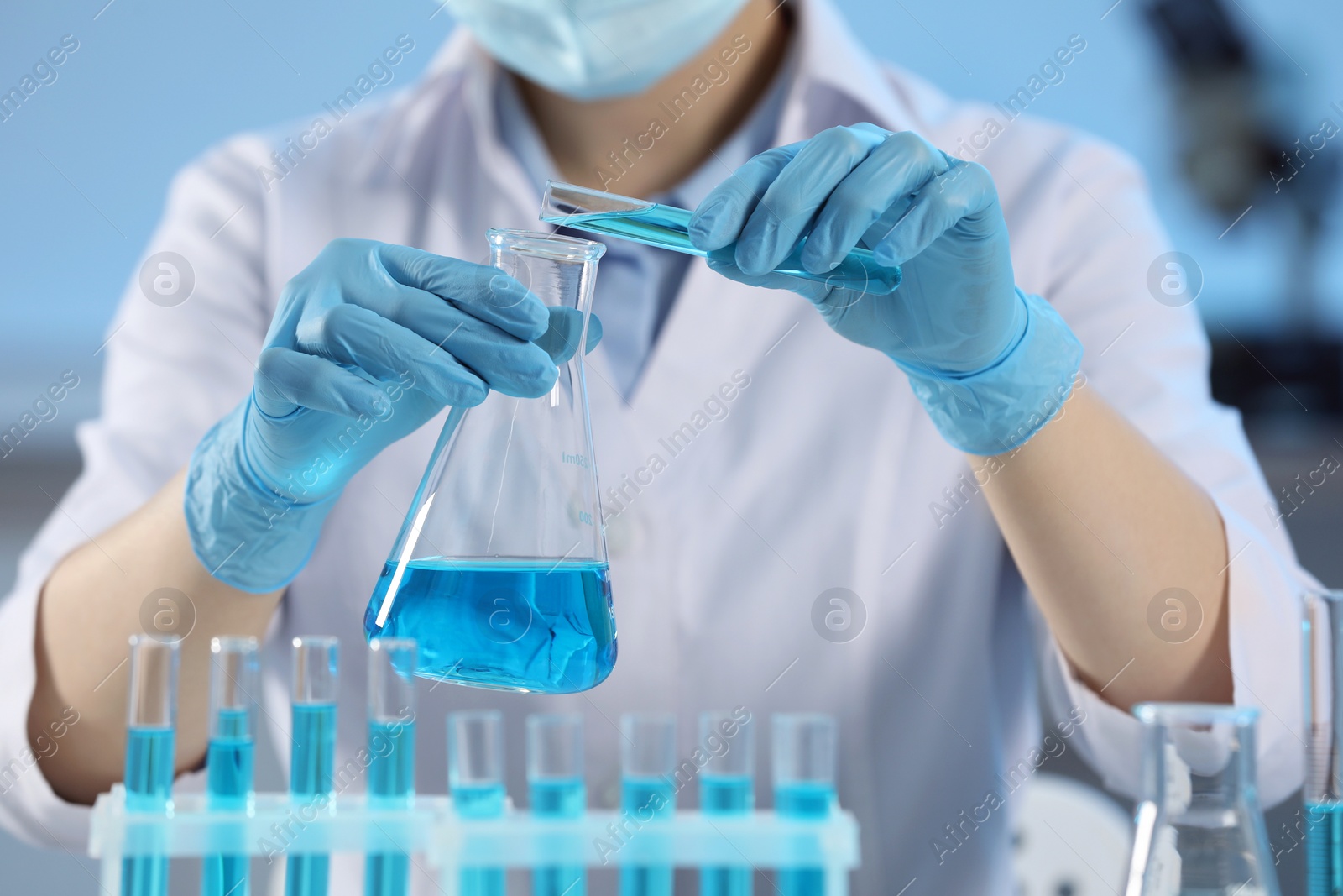 Photo of Scientist working with beaker and test tube in laboratory, closeup